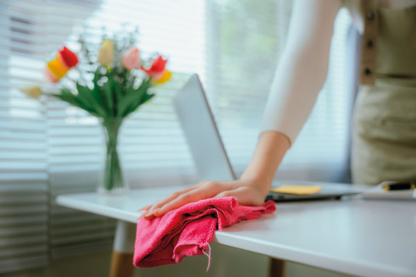 Reinigungskraft säubert Büroarbeitsplatz – professionelle Office-Reinigung für ein gepflegtes Arbeitsumfeld